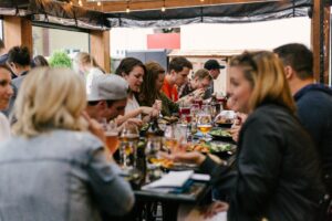 grupo de pessoas comendo e bebendo em evento corporativo sentados a mesa
